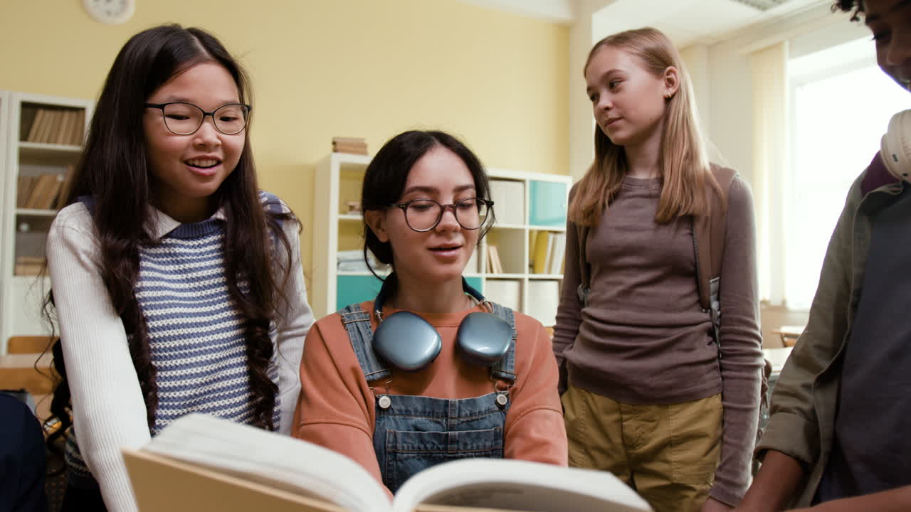 Diverse group of students reading a book together in a classroom