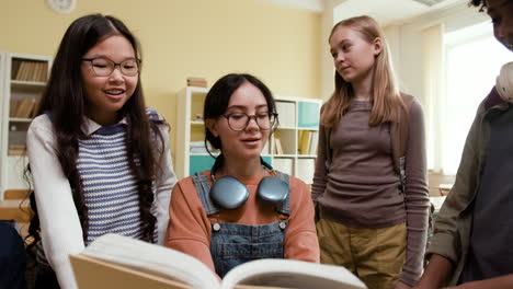 diverse group of students reading a book together in a classroom