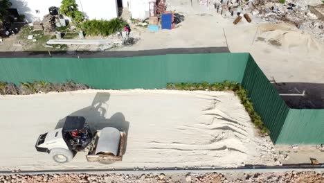 tractor crushing sand floor for construction project, drone aerial shooting