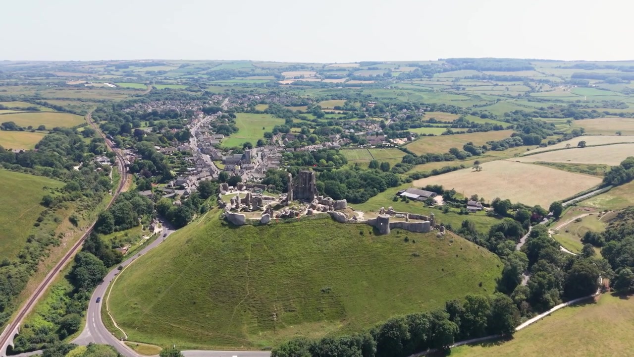 Corfe Castle Isle of Purbeck Dorset, England, flight over castle and village alongside Swanage to Corfe railway with views of the surrounding countryside on bright sunny day