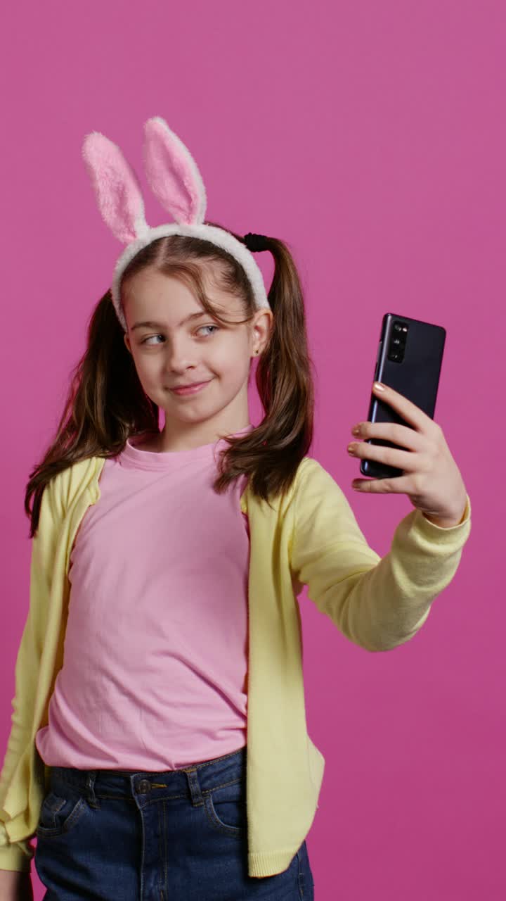 Ragazza spensierata con orecchie da coniglio che scatta selfie con lo smartphone