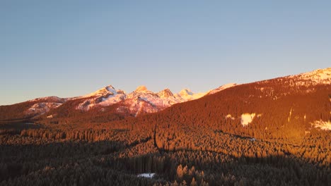 nature captured with a drone with landscape and mountains covered in snow at golden hour at sunrise with beautiful forest and surrounding hills captured in slovenia above forest pokljuka in 4k