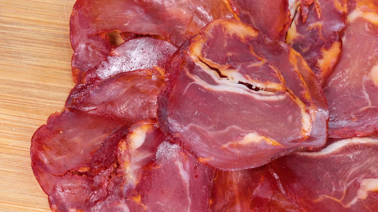 Traditional air dried pork loin slices, macro shot view from above, rotating motion