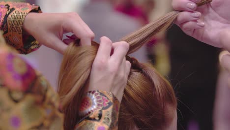 close up of hairdresser with fashionable jacket red nails creating hairstyle on brunette female slow motion