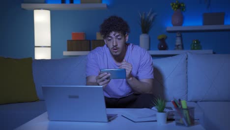 Young-man-looking-at-the-phone-in-amazement.-At-home-at-night.