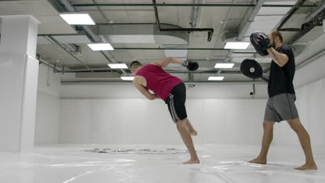 by fighting a mma with a trainer he works out the striking technique of arms and legs training the reaction of dives and deviations from strikes. workout with a partner on the paws of blows.