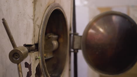 close-up of a worker opening a kiln door using a manual lever, focus on hand in protective glove against the white kiln