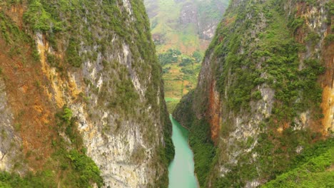 aerial dolly forward through steep canyon walls over the gorgeous turquoise blue green water of the nho que river in northern vietnam