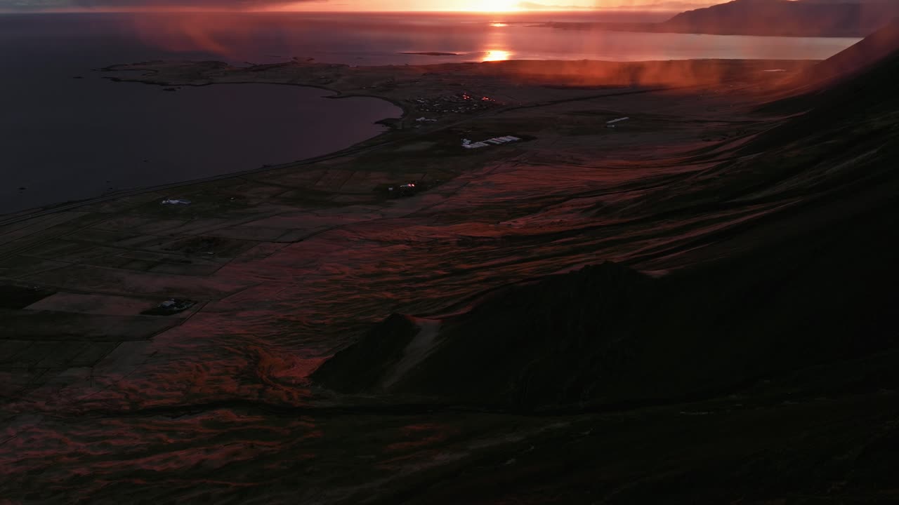 A stunning sunset casts a deep red glow over the rugged Akranes mountains in Iceland, creating a dramatic and vibrant landscape
