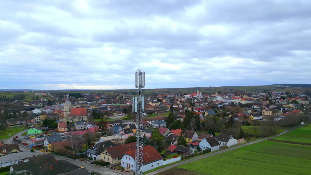воздушная орбита вокруг вышки сотовой связи в сельском пейзаже с домами в пасмурный день