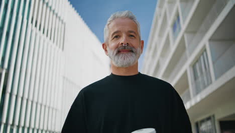 elderly man looking camera on street closeup. smiling bearded senior drinking
