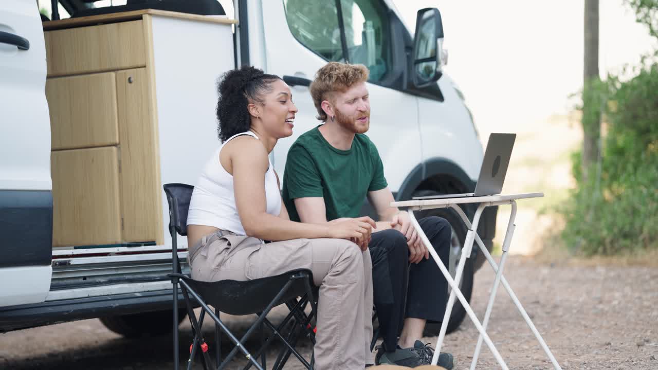 Couple working on a laptop by a van