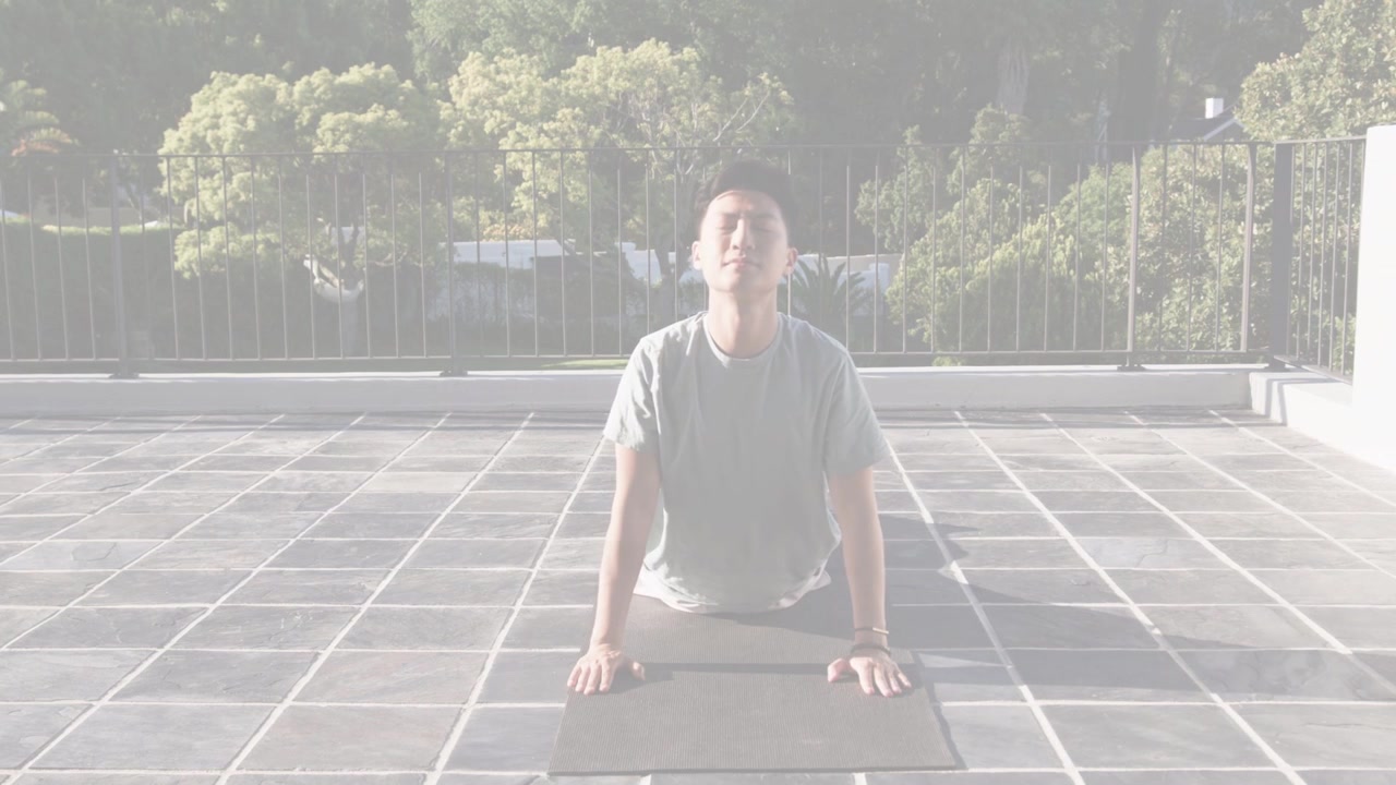 Man shifting hips from prayer into lifted chest cobra on tiled rooftop mat, doing fitness stretch
