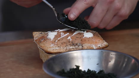 topping delicious grilled salmon steak with black caviar