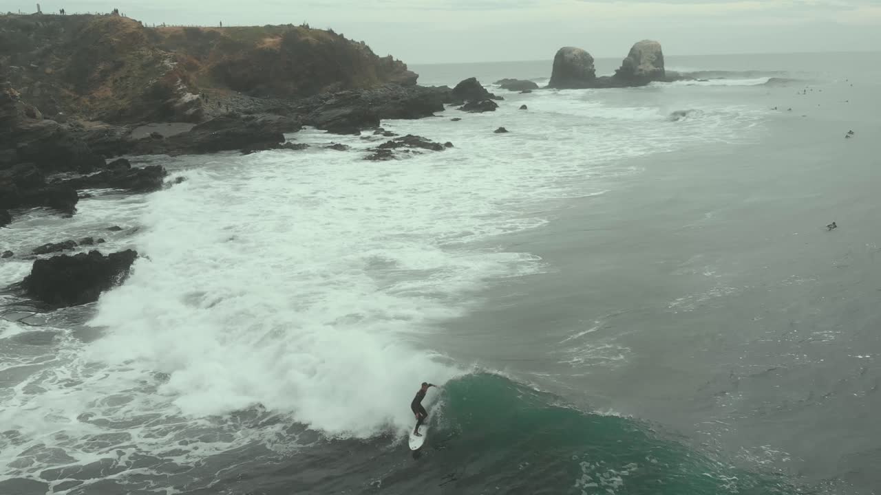 Surfer riding waves near rocky coast