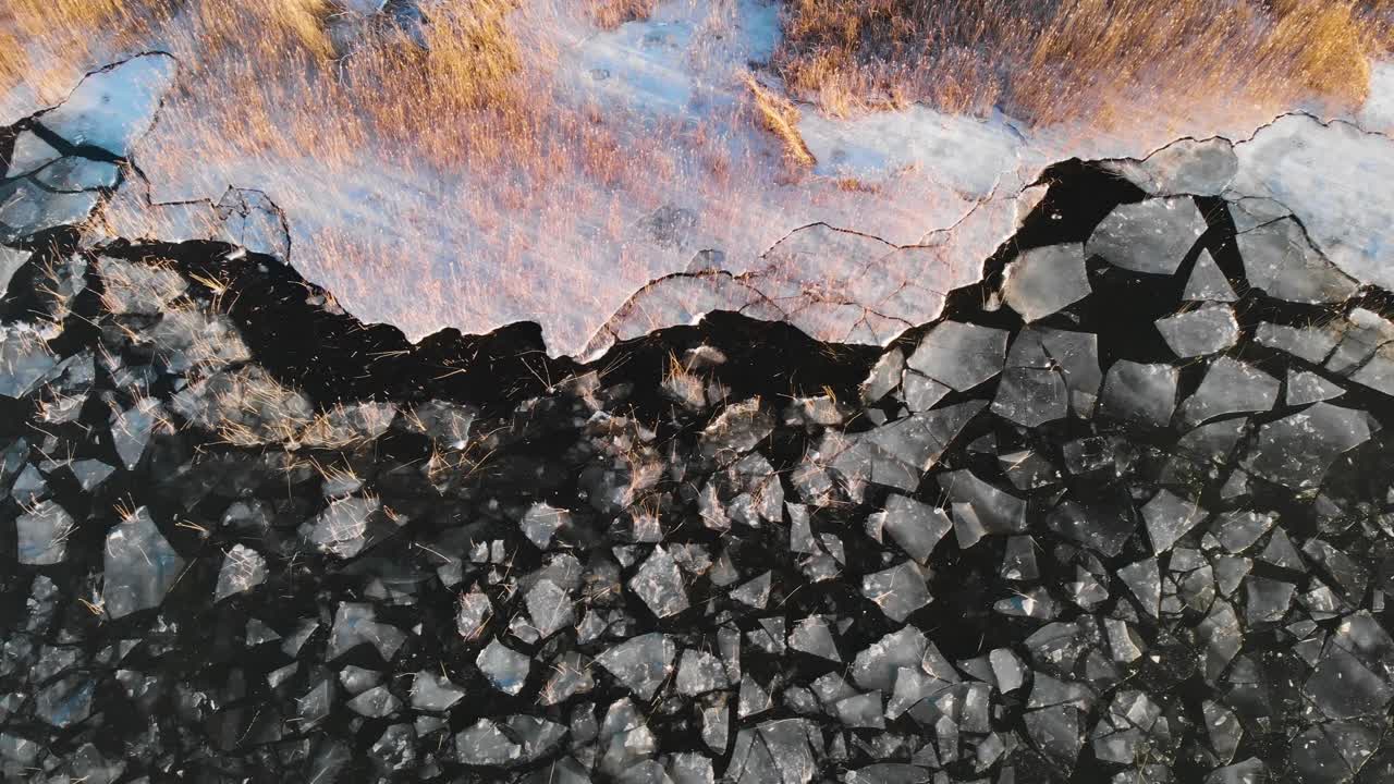 toma aérea de la costa de un lago cubierta de hielo agrietado, paisaje invernal congelado