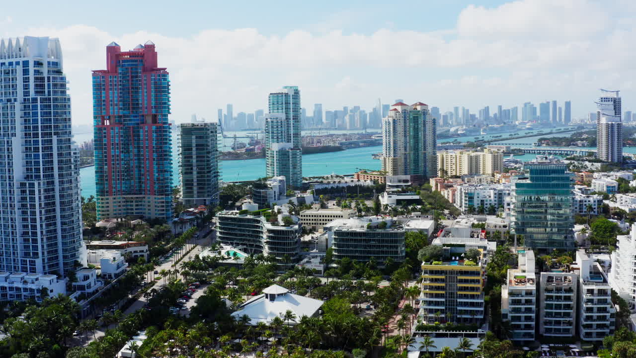 A smooth drone flyout reveals the vibrant skyline of South Beach, Miami, with turquoise waters and downtown skyscrapers in the distance.