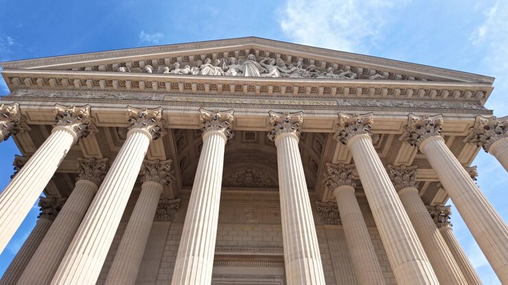 Facciata della Chiesa della Madeleine con alte colonne corinzie e sculture dettagliate sul frontone, incorniciata contro un cielo azzurro brillante