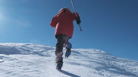 man runs along steep snowy slope from behind in slow motion