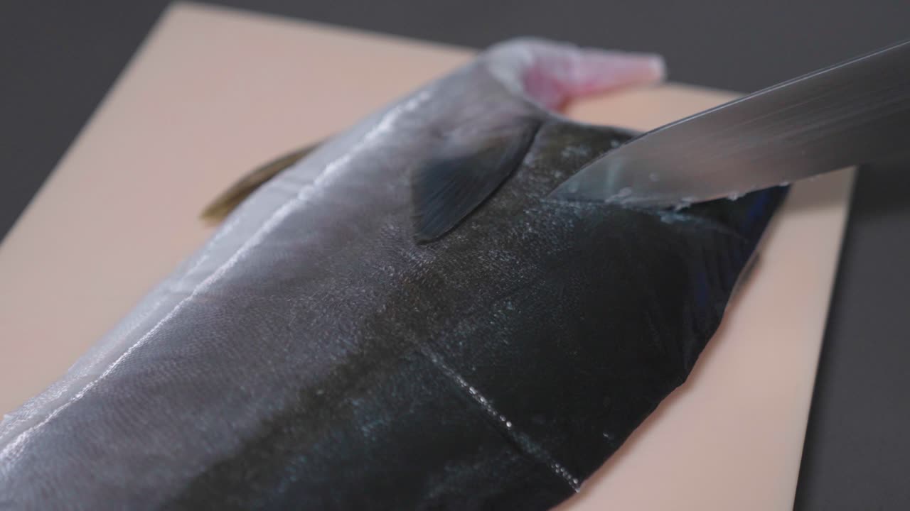 A static shot captures a chef removing small pieces from a fish during preparation, showcasing precision and care. Ideal for culinary, seafood, and kitchen content.