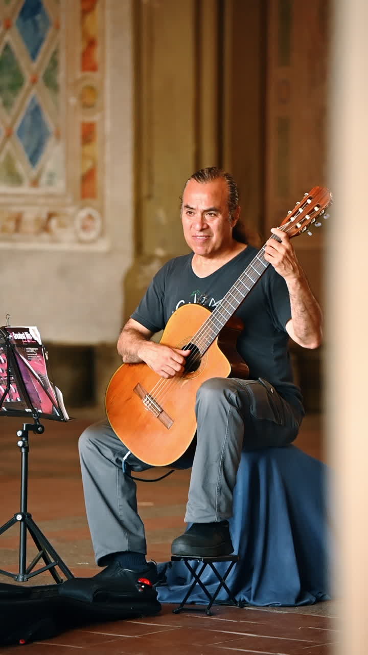 New York, AS, 25 Juli 2025: Musisi jalanan bermain gitar di Central Park. Musisi jalanan menampilkan musik gitar di dalam lorong Central Park dengan pejalan kaki