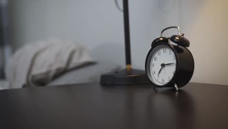 close-up footage of a person reaching to turn off an alarm clock on a bedside table