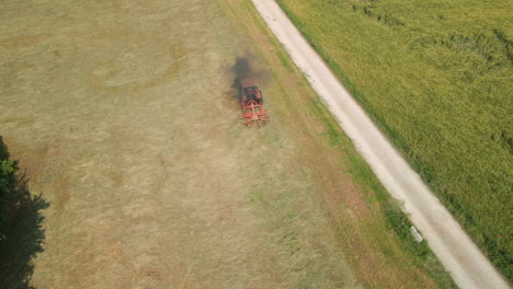 Raking-Freshly-Cut-Hay-In-The-Farm-With-Rotary-Rake-Pulled-By-A-Tractor