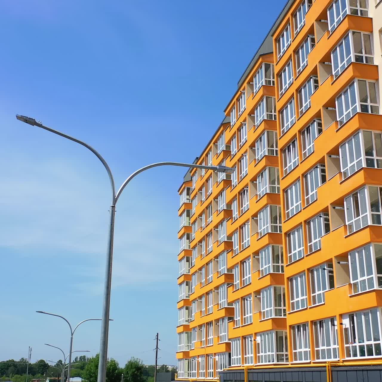 Modern skyscraper of bright color. New multi storey building in the city. Side view of contemporary high-rise against blue sky background