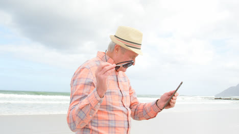 Side-view-of-old-caucasian-senior-man-using-digital-tablet-at-beach-4k