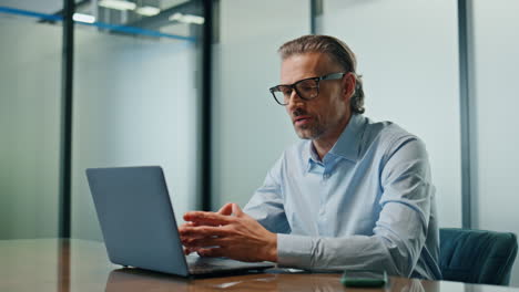 focused businessman calling laptop at conference room. eyeglasses man talking