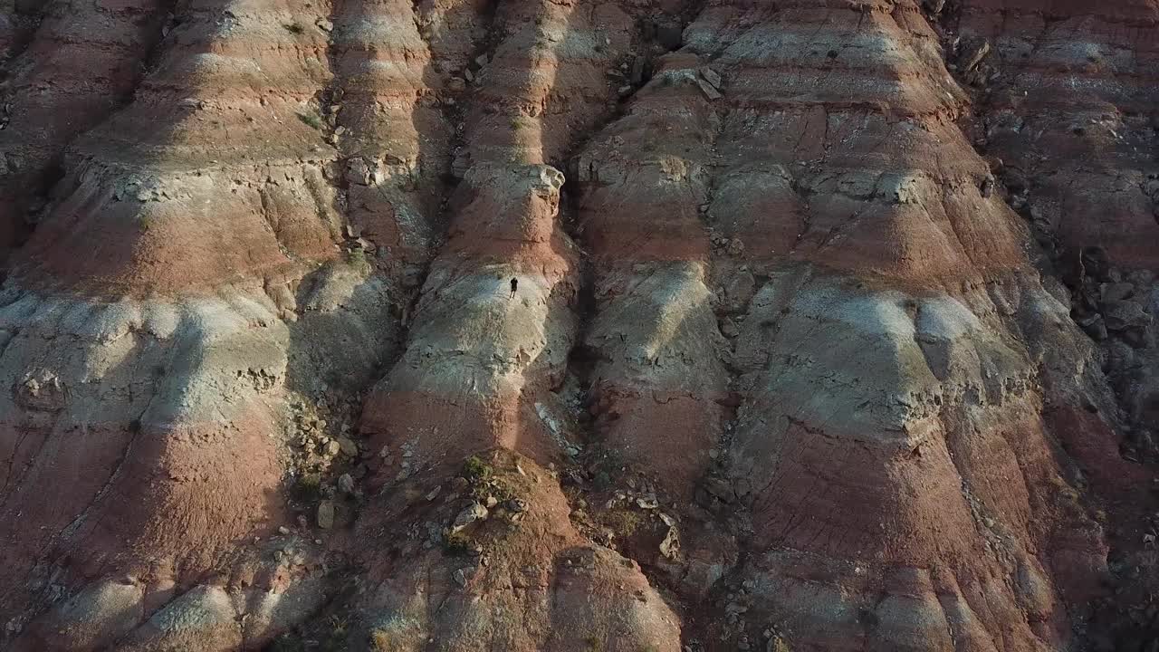 hombre de pie en el acantilado de formación de roca arenisca en el desierto de utah, vista aérea