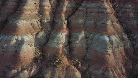 male standing on sandstone rock formation cliff in utah desert, aerial view