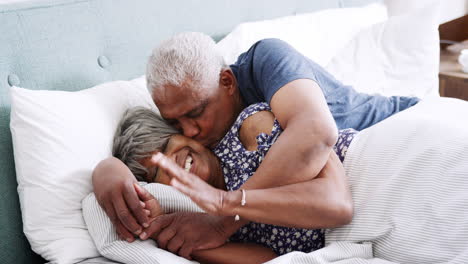 loving senior couple cuddling in bed in morning