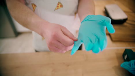Man-wearing-gloves-at-the-kitchen-in-a-close-up-view