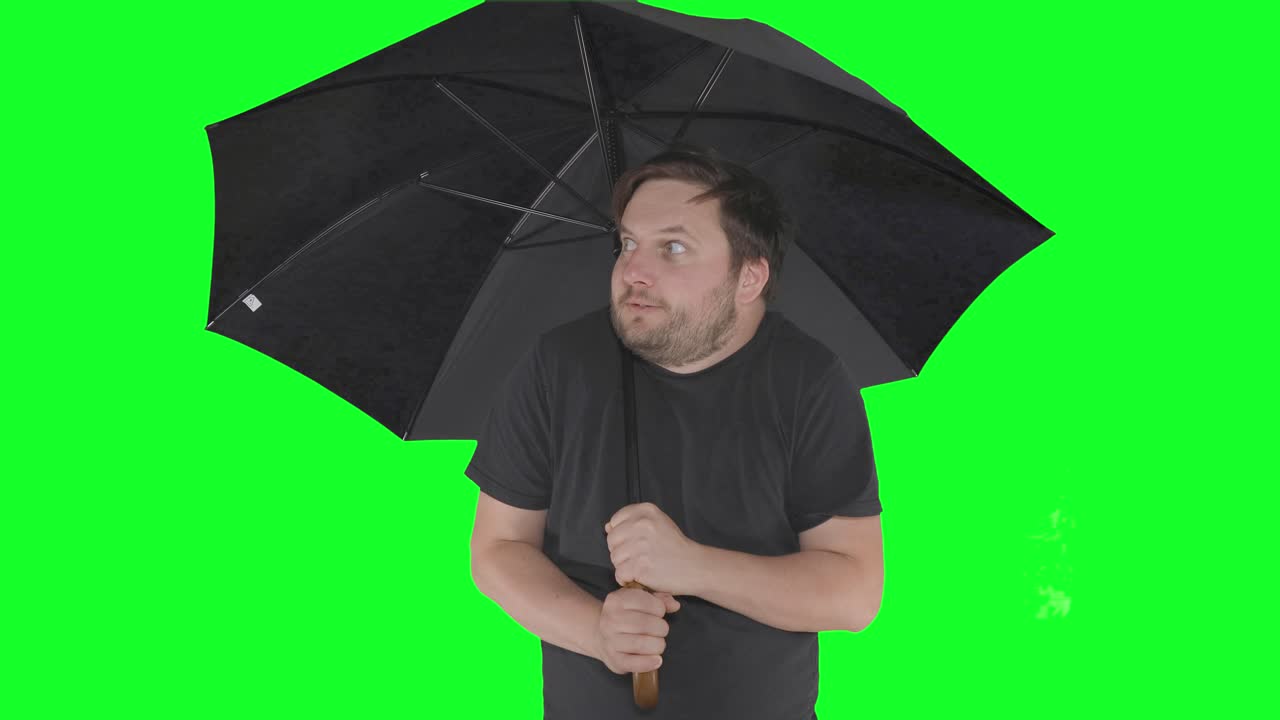 uomo spaventato dalla pioggia sotto l'ombrello nero, sfondo dello schermo verde, meme di ragazzo divertente