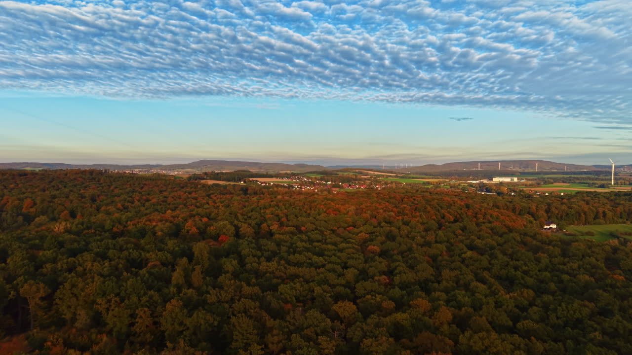 Stunning autumn landscape of colorful trees and rolling hills at sunset with a vibrant sky filled with clouds