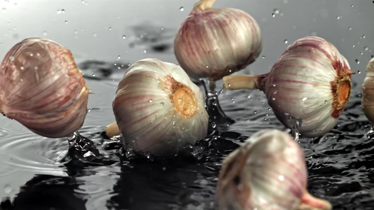 Bulbi d'aglio freschi che cadono nell'acqua con schizzi