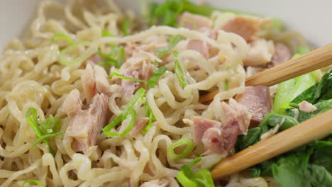 picking bakmi chinese noodles with wooden chopsticks