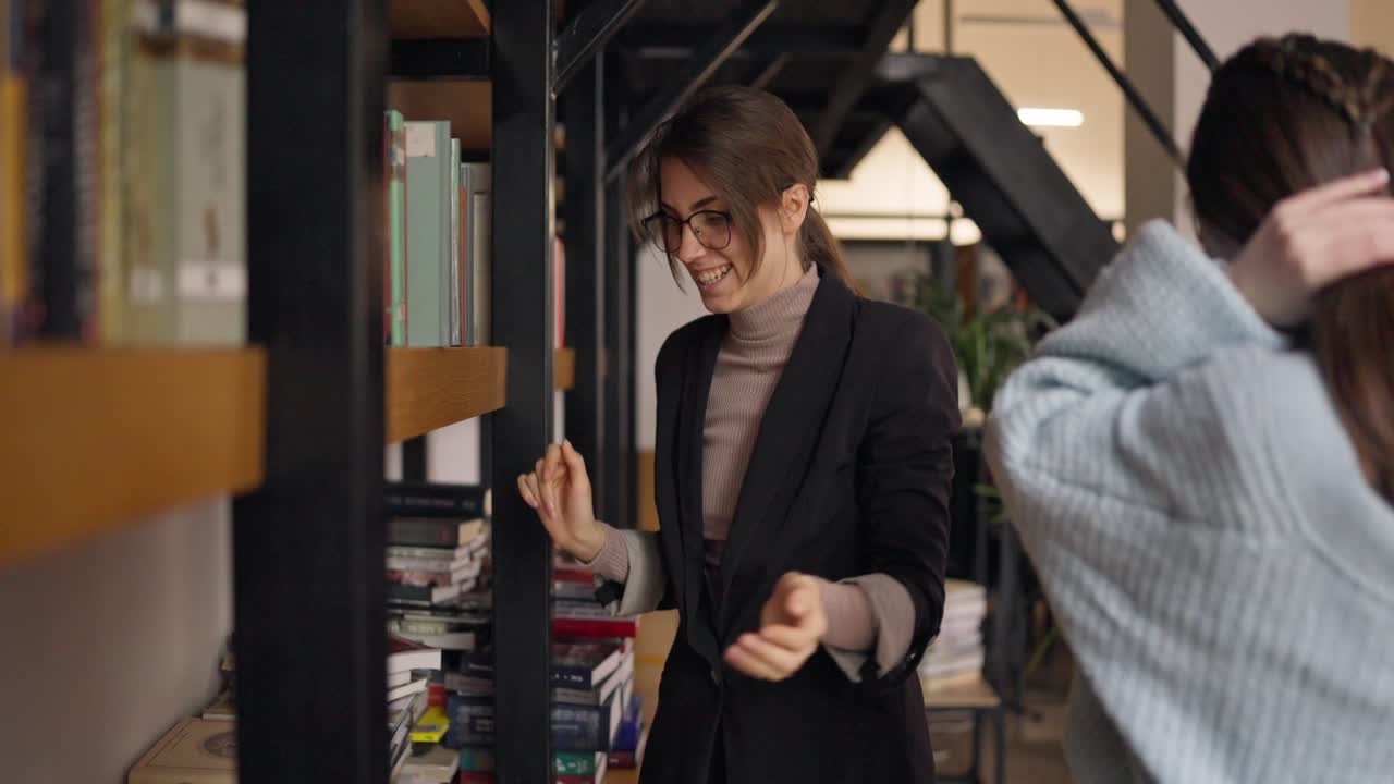 Two young women browsing books in a library