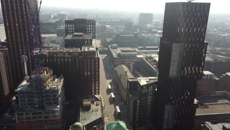 aerial drone flight along oxford road in manchester city centre showing new towers and buildings under construction with people and traffic below