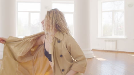 focused blonde woman in trench coat and boots training a contemporary dance in the middle of the studio 1