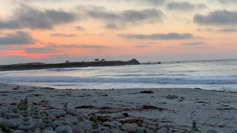 magnífica puesta de sol en pebble beach, california con surfistas montando olas en el fondo