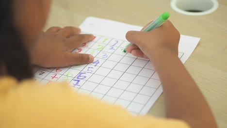 child writing numbers on worksheet