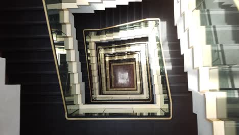 mirando hacia abajo las escaleras cuadradas de vidrio y metal en un edificio de oficinas moderno