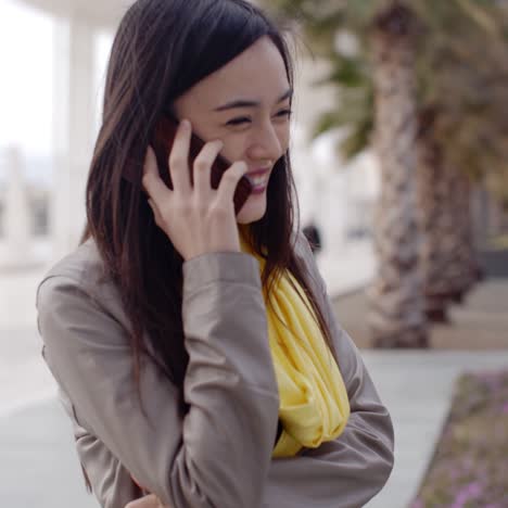mujer joven de pie hablando por su teléfono móvil