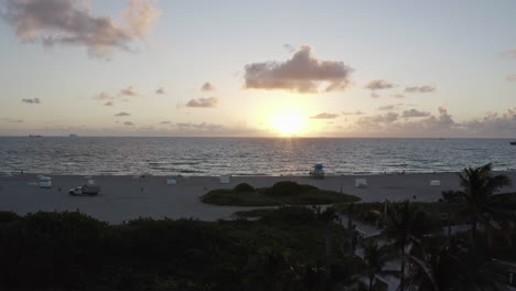 Schöner-Sonnenaufgang-über-South-Beach-Miami-Mit-Palmen-Im-Vordergrund,-Die-Den-Ozean-Enthüllen