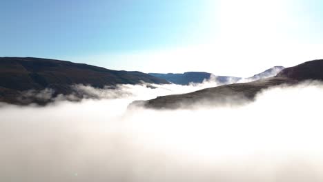 aerial orbiting shot of the icelandic mountains above low-lying clouds in the valley