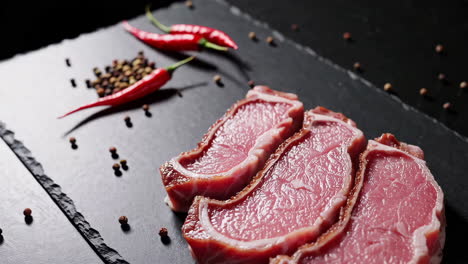 raw beef steaks with chili peppers and spices