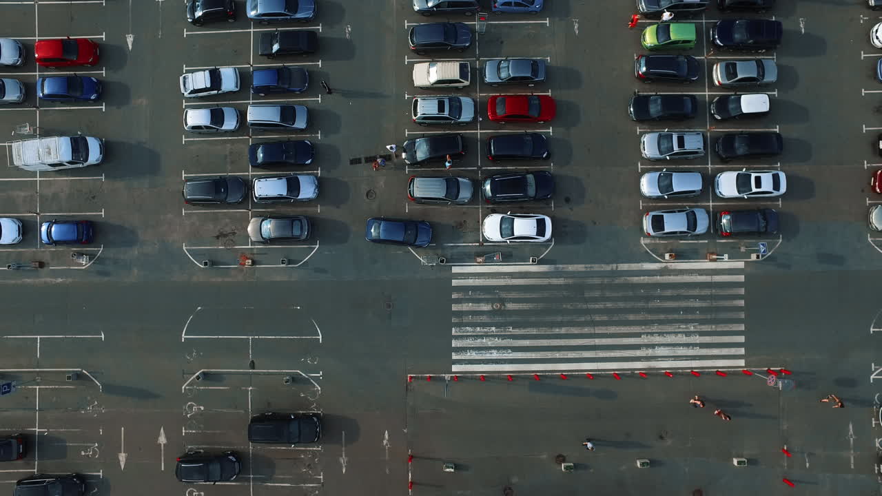Riprese con drone di persone che camminano nel parcheggio. Elicottero che filma un parcheggio con persone.