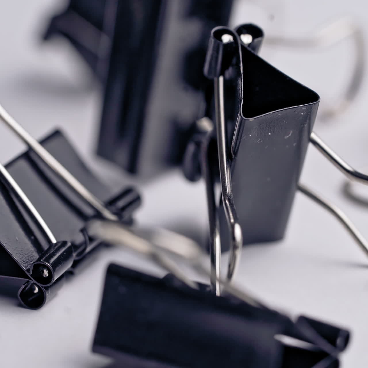 Black paper clips rotate on white background. Office supplies
